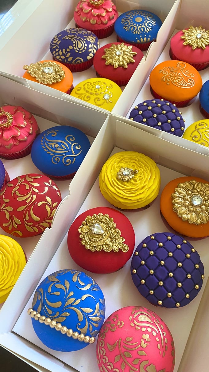 an assortment of colorful Indian cupcakes in a box